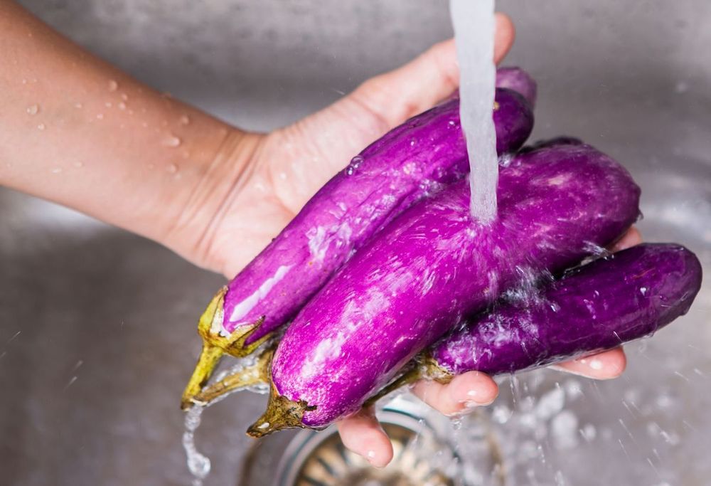 Rửa sạch cà tím dưới vòi nước chảy